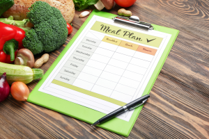 A clipboard with a sheet of paper that has Meal Plan at the top and the days of the week.