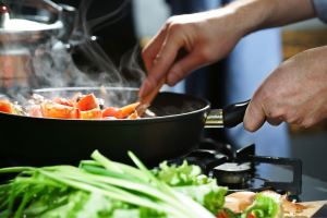 Close up of frying pan with man cooking